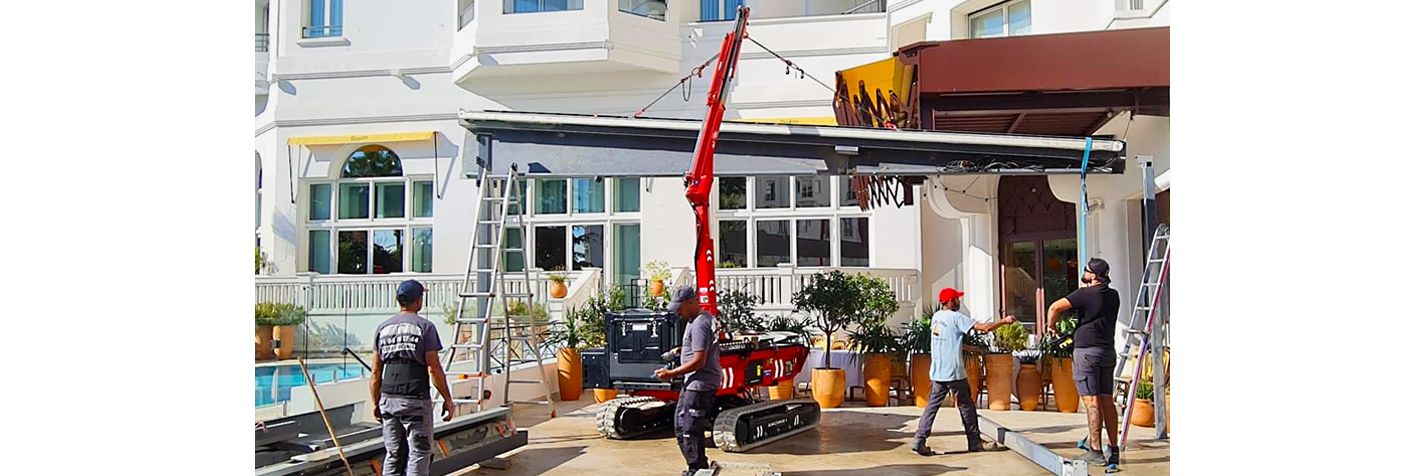 Alma Crawler Multi-Loader 6.0 BL nostaa kattorunkoa rakennustyömaalla.