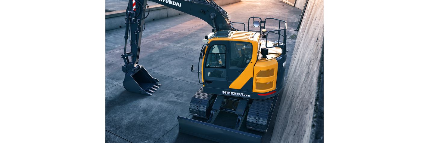 Telakaivinkone Hyundai HX 130 ALCR pysäköitynä rakennuksen seinustalle
