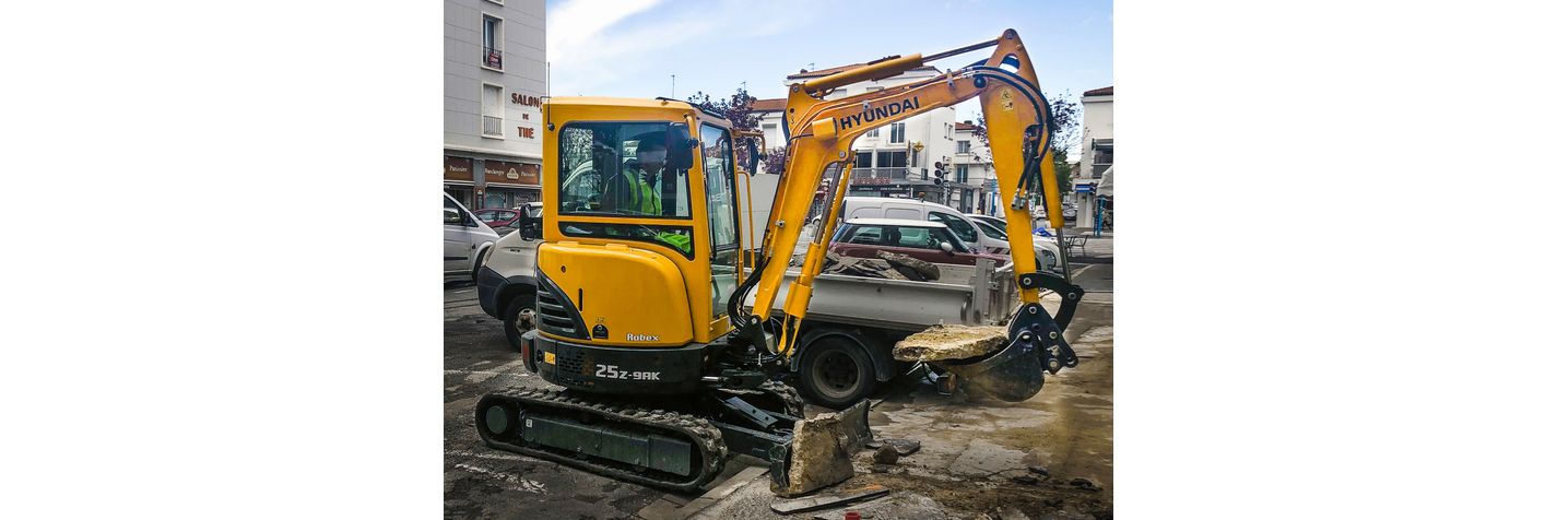 Minikaivinkone Hyundai R 25 Z-9AK nostaa laattaa parkkipaikalla