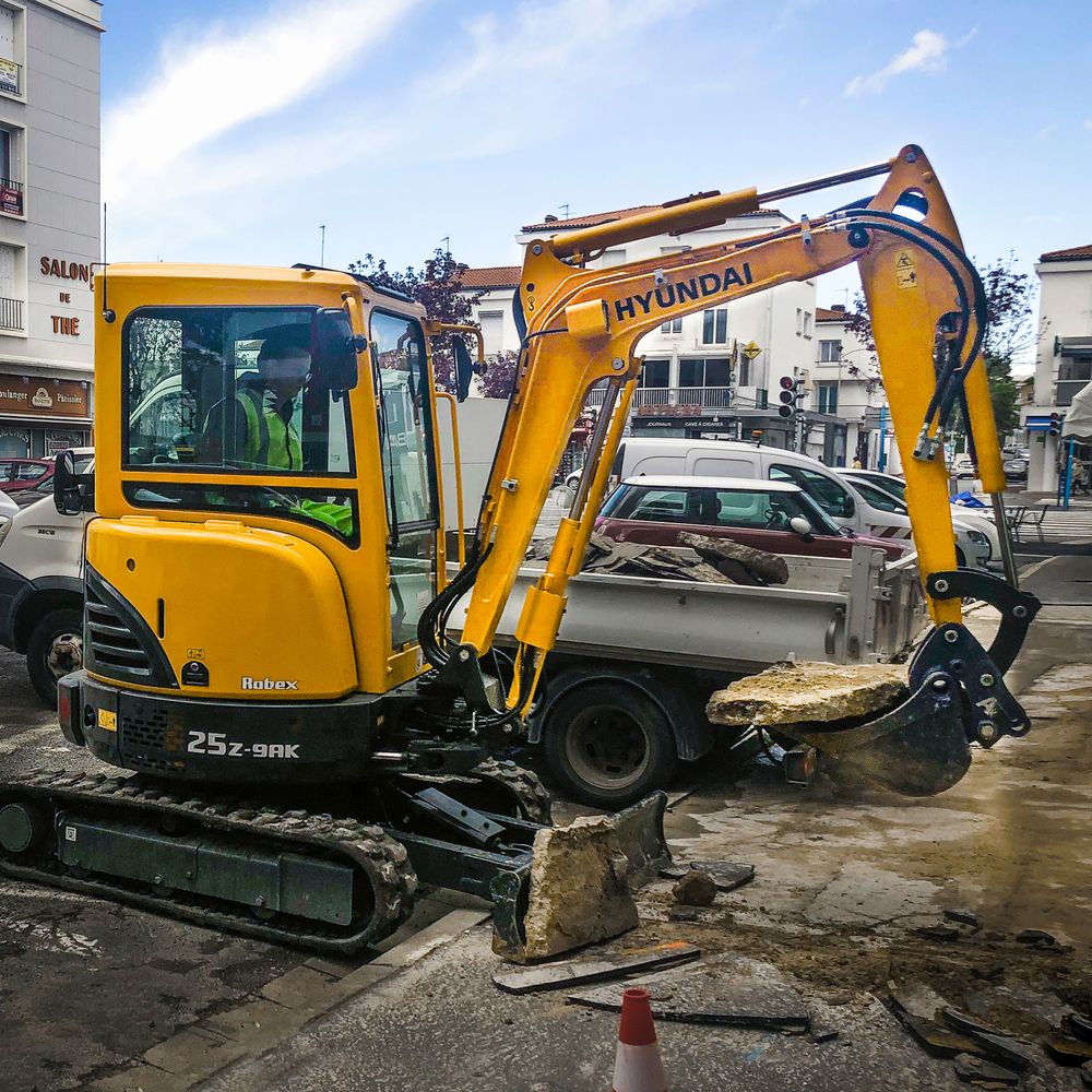 Minikaivinkone Hyundai R 25 Z-9AK nostaa laattaa parkkipaikalla